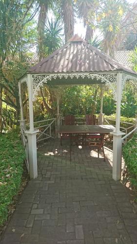 a gazebo with a picnic table and a bench at Country Blue Luxury Guest House in Polokwane