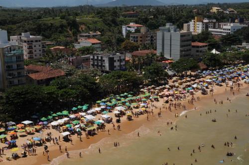 a crowd of people on a beach with umbrellas at Pousada Maravista in Anchieta