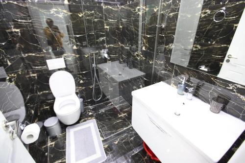 a black tiled bathroom with a toilet and a sink at Hotel Erviliano in Borsh