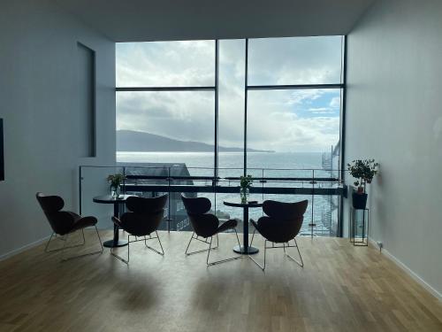 une salle à manger avec une table, des chaises et une grande fenêtre dans l'établissement Hotel Djurhuus, à Tórshavn