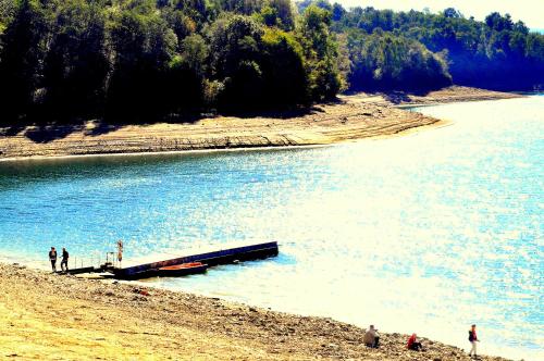 a group of people standing on a beach near a body of water at Domki Olina in Polańczyk