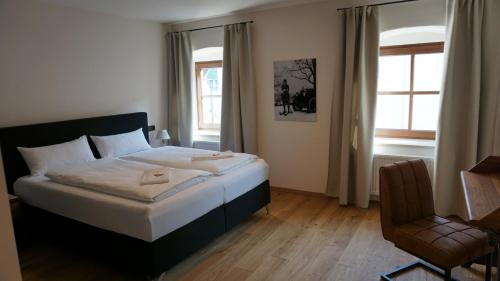 a bedroom with a bed and a chair and a window at Hotelgasthof Kirchenwirt in Schierling