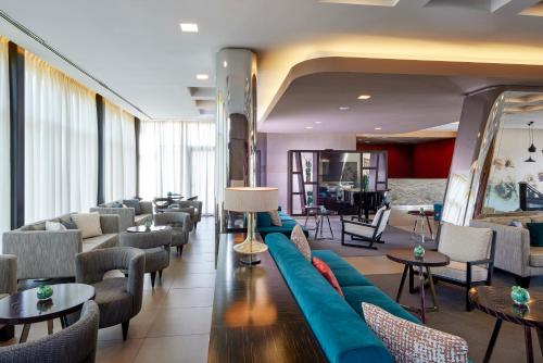 a lobby with a blue couch and chairs and tables at Blu Hotel Brixia in Castenedolo