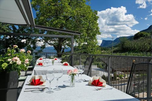 una mesa con copas de vino y flores en el balcón en Gasthof Falger, en Foiana - Völlan