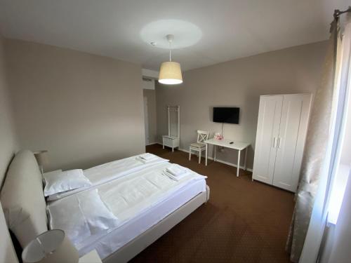 a bedroom with a large white bed and a desk at B&B Andero Deva in Deva