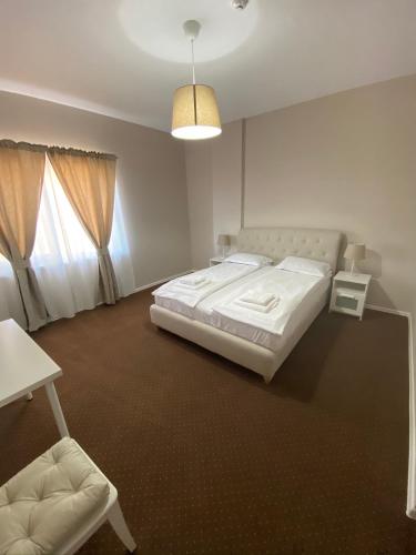 a white bedroom with a bed and a chair at B&B Andero Deva in Deva
