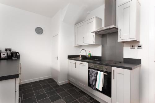 a kitchen with white cabinets and a sink at McLaren House Seahouses in Seahouses