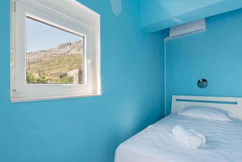 a blue room with a bed and a window at Holiday home Giovanni in Solin