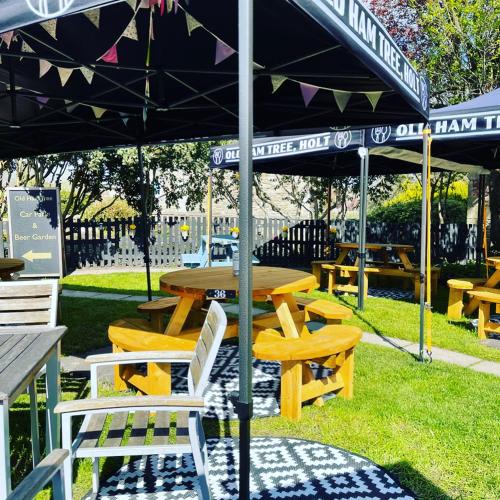 a picnic table and chairs under an umbrella in a park at The Old Ham Tree in Holt