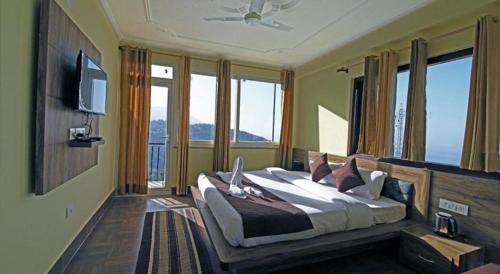 a bedroom with a large bed in a room with windows at Hotel Harmony Blue Mcleodganj, Dharamshala in Dharamshala