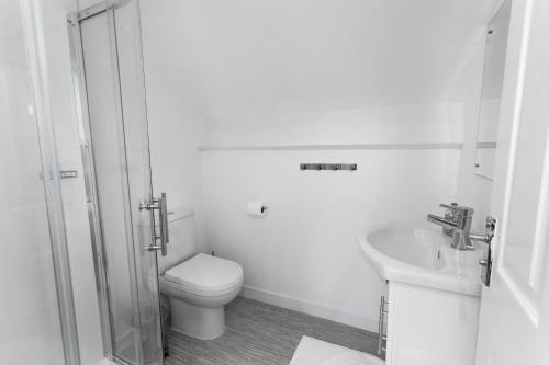 a white bathroom with a toilet and a sink at McLaren House Seahouses in Seahouses