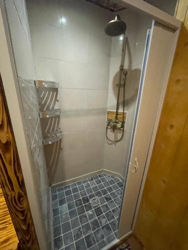 a shower with a glass door and a blue tile floor at gite du vieux bourg in Le Vieux Bourg