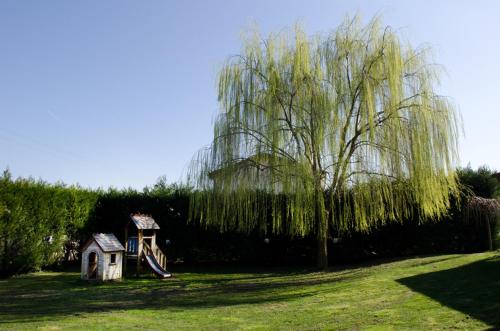 a weeping willow tree and a small house in a yard at Osteria e Locanda Del Viaggiatore in Russi