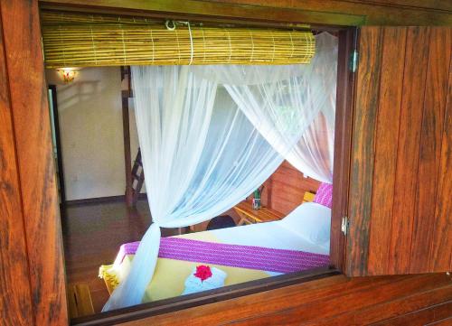 a glass window of a room with a bed and curtains at Pousada Horizonte Azul in Ilha de Boipeba