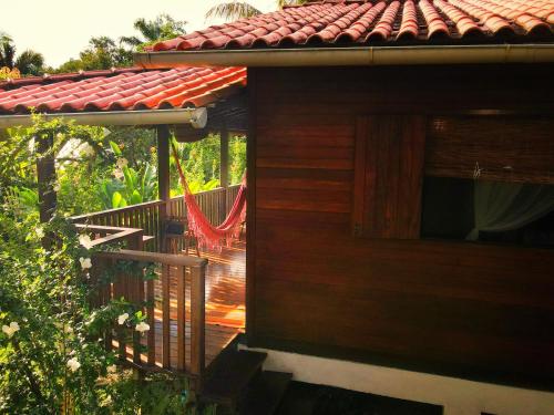 a wooden deck with a hammock on the side of a house at Pousada Horizonte Azul in Ilha de Boipeba