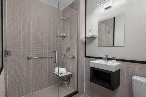 a bathroom with a shower with a sink and a mirror at The Baltic Hotel in Brooklyn