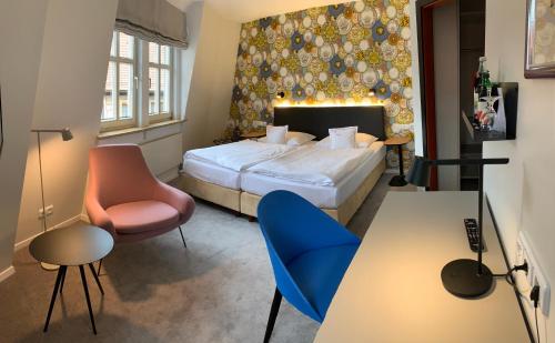 フォルカッハにあるHotel am Torturmのベッド、テーブル、椅子が備わるホテルルームです。