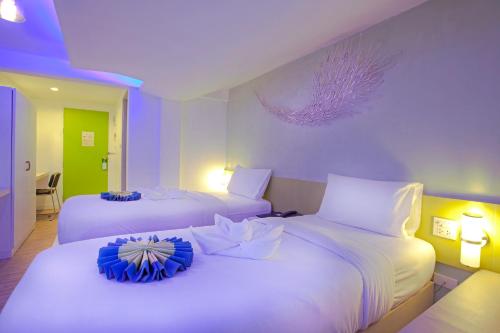 two beds in a room with purple and white at Holidays Home in Pattaya South