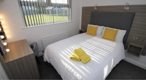 a bedroom with a large white bed with yellow pillows at Guest Rooms @ 128 in Portrush