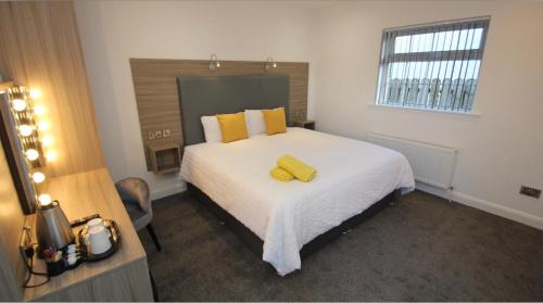 um quarto com uma grande cama branca com almofadas amarelas em Guest Rooms @ 128 em Portrush