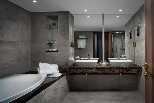 ein Badezimmer mit zwei Waschbecken, einer Badewanne und einer Badewanne in der Unterkunft The Savoy Hotel in Limerick
