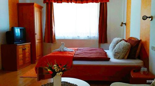 a bedroom with a bed with a red blanket and a window at Guesthouse Kohári in Egerszalók