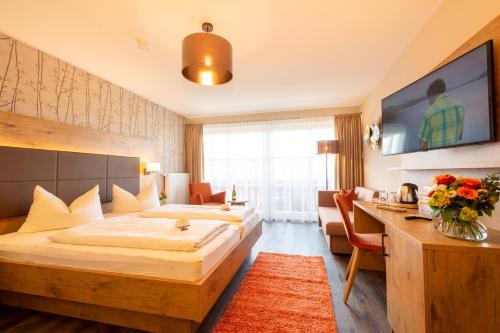 a hotel room with two beds and a desk at Boutique Hotel Angerer in Murnau am Staffelsee