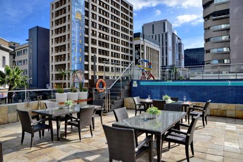 a rooftop patio with tables and chairs and buildings at Cresta Grande Cape Town in Cape Town