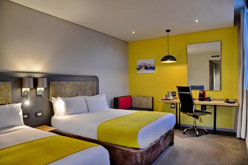 a hotel room with two beds and a desk at Cresta Grande Cape Town in Cape Town