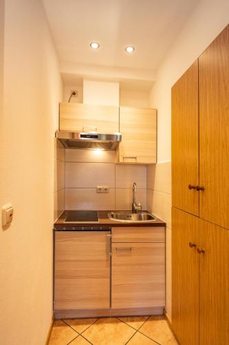 a small kitchen with wooden cabinets and a sink at Boutique Hotel Angerer in Murnau am Staffelsee