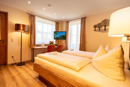 a hotel room with a bed and a desk and window at Boutique Hotel Angerer in Murnau am Staffelsee