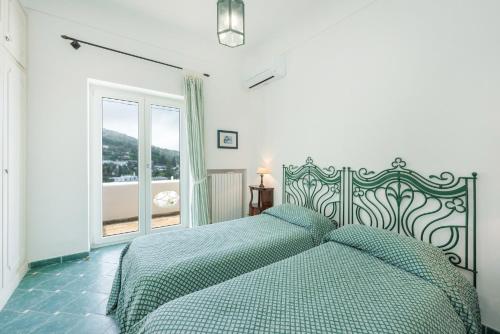 sypialnia z łóżkiem z zieloną kołdrą i oknem w obiekcie Casa Ventrosa, Anacapri w mieście Anacapri