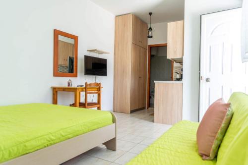 a bedroom with a green bed and a kitchen at Kalithies Studios CDK in Kalithies