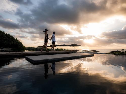 a man and a woman walking on a dock by a pool at NIZUC Resort & Spa in Cancún