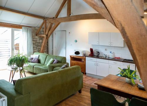 a living room with two green couches and a kitchen at Holiday Homes Gillishof in Simpelveld