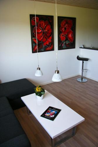 a living room with a coffee table and two paintings at Gydensgaard ferielejligheder på Læsø in Læsø