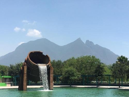 a water fountain in a pool with mountains in the background at Wyndham Garden Monterrey Norte in Monterrey