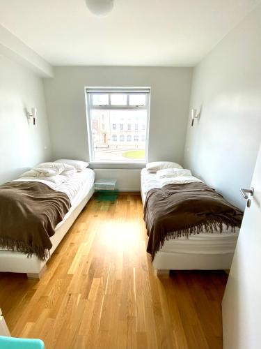 two beds in a room with a window at Day Dream Townhall Square Apartments in Akureyri