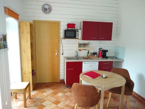 a small kitchen with red cabinets and a table at Ferienwohnung Amende in Angermünde