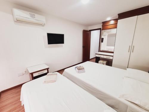 a hotel room with two beds and a television at Flat Pasárgada 712 - apt com vista para a Praia da Costa, academia moderna, piscinas panorâmicas, minimercado e lavanderia in Vila Velha