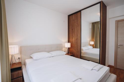 a bedroom with a large white bed and a mirror at Status-M Apartments 176 in Bečići
