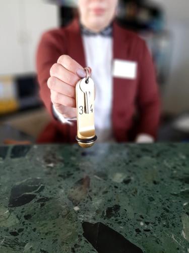 a man is holding a key to a table at Hotel Pelikán in Lučenec