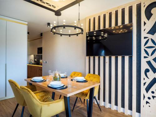 a dining room with a wooden table and yellow chairs at Aparthotel Góralski Spa 2 in Białka Tatrzanska