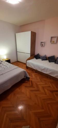 a bedroom with two beds and a wooden floor at Apartmani Nikica in Drage