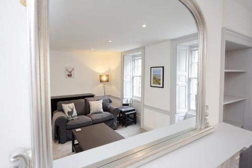 a mirror reflecting a living room with a couch at ALTIDO Elegant New Town Flat near Princes Street in Edinburgh