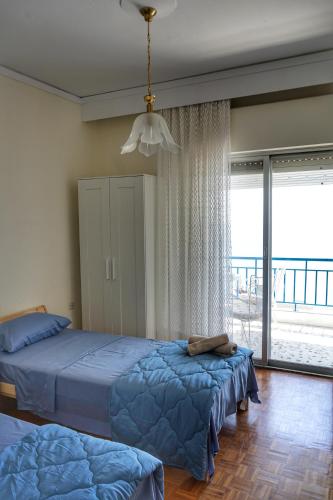 a bedroom with two beds and a large window at Liana`s apartment in Paleo Tsifliki