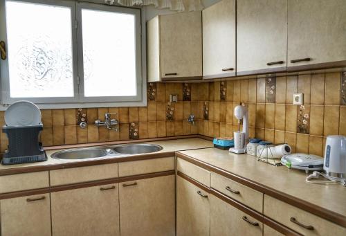 a kitchen with wooden cabinets and a sink and a window at Liana`s apartment in Paleo Tsifliki