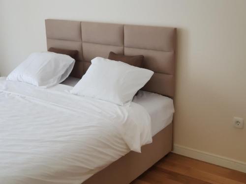 łóżko z białą pościelą i poduszkami w pokoju w obiekcie Apartman VIVO city central w mieście Podgorica