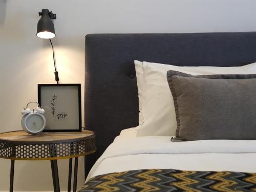 a bedroom with a bed and a table with a clock on it at Aeropod Sovo Kota Kinabalu By LAXZONE in Kota Kinabalu