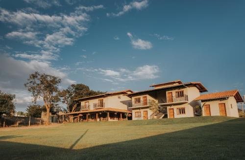 a large house with a grass field in front of it at Pousada Cheiro da Terra in Capitólio